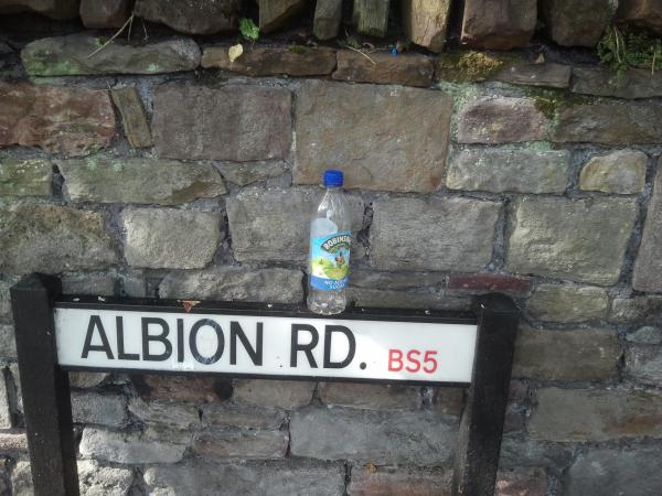 discarded bottle placed on street sign